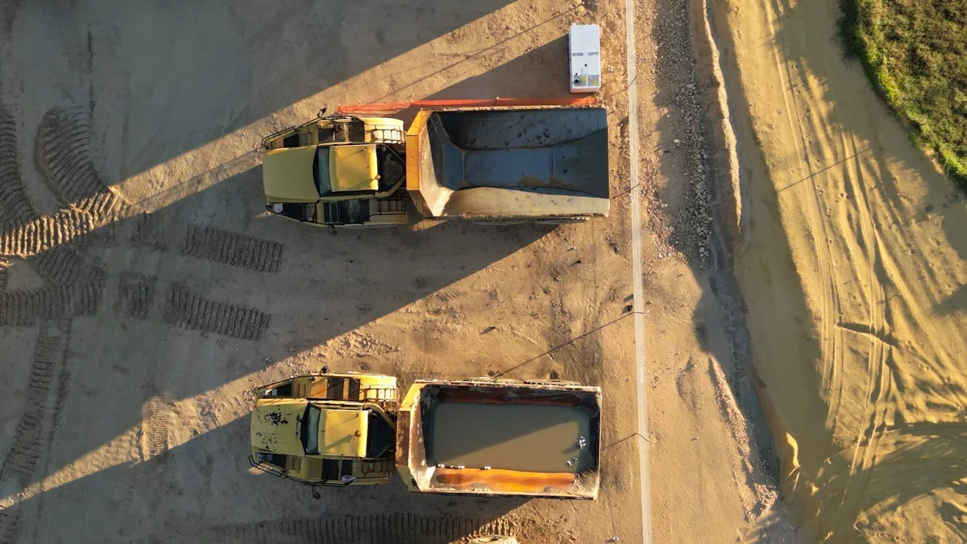 A group of dump trucks parked side by side at a jobsite staging area