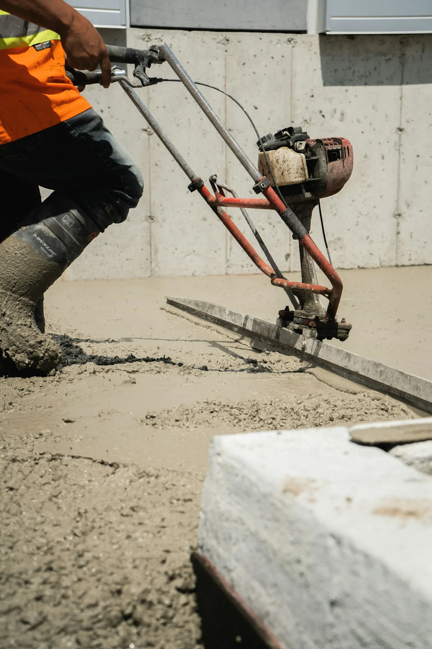 Worker using equipment to pour concrete on a construction site